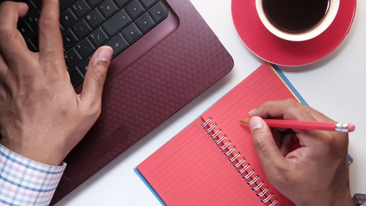 Person working on laptop and taking notes