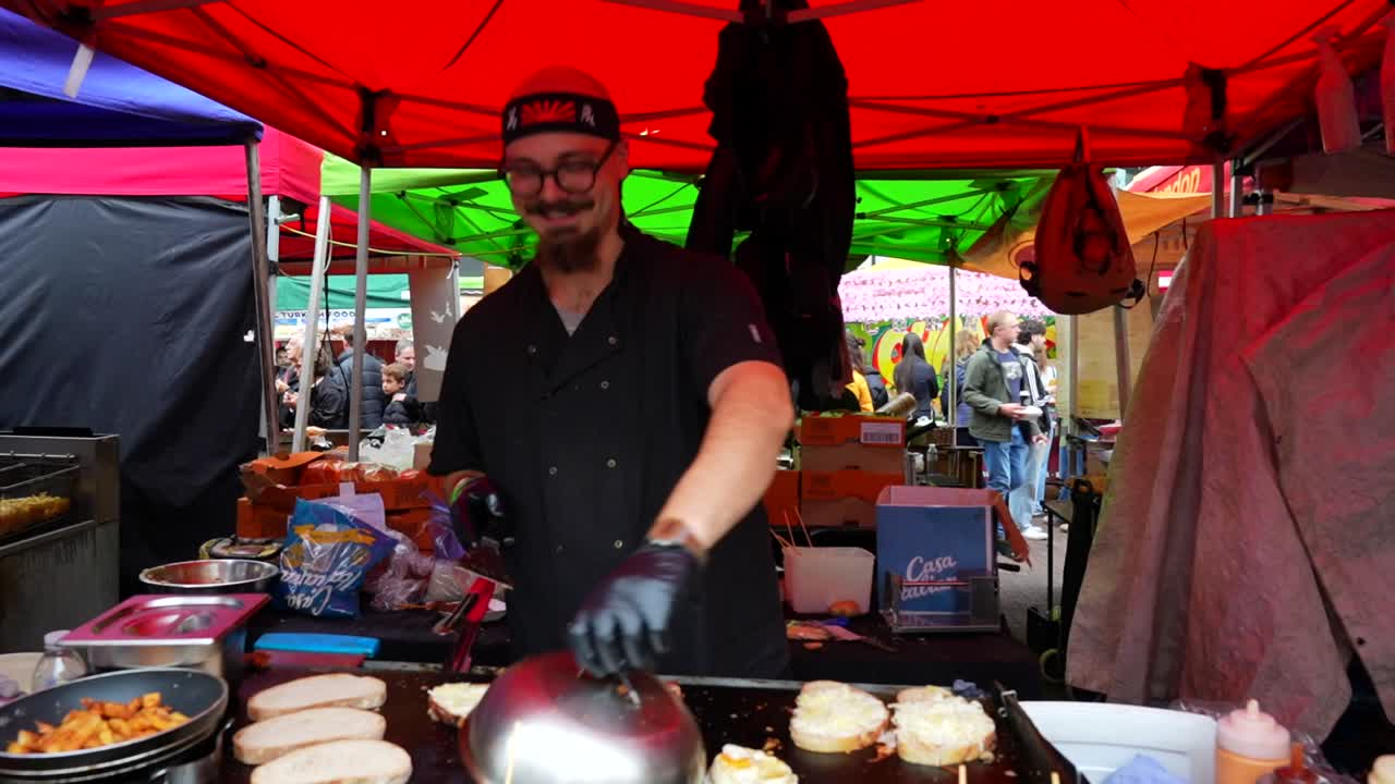 Street food chef at work, laughing at the people in Portobello Road, Notting Hill, London