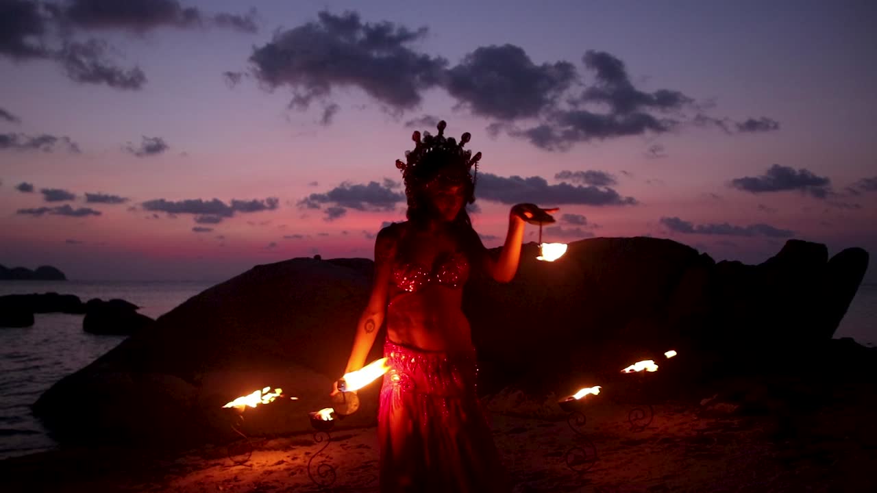 e sensuale danzatrice del ventre, che esegue movimenti rotatori con torce di fuoco a palma, sulla spiaggia durante l'ora d'oro. Rallentatore