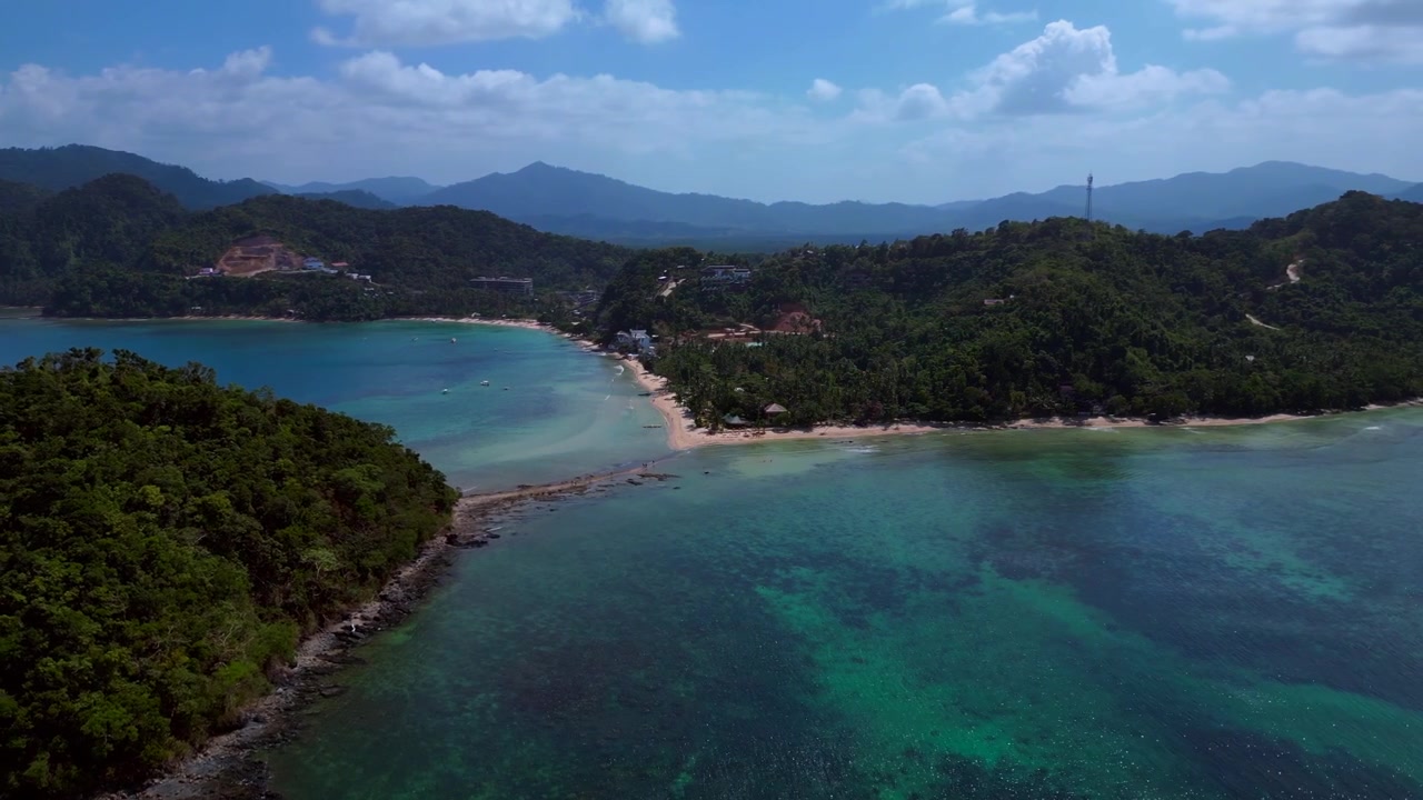 Las Cabanas Beach shoreline with lush green jungle hills, clear shallow water, and people enjoying the tropical scenery. Fantastic aerial view wide orbit drone panorama overview