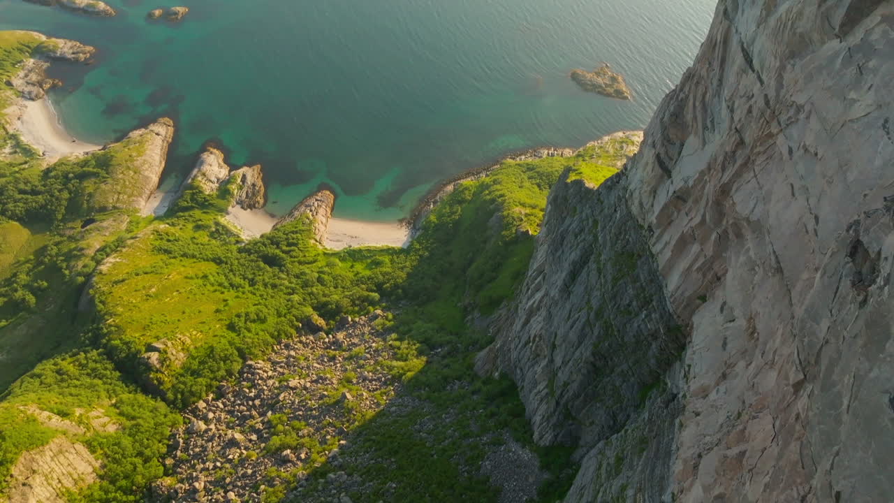 Female hiker on cliff edge overlook scenic Norway islands in midnight sun; drone