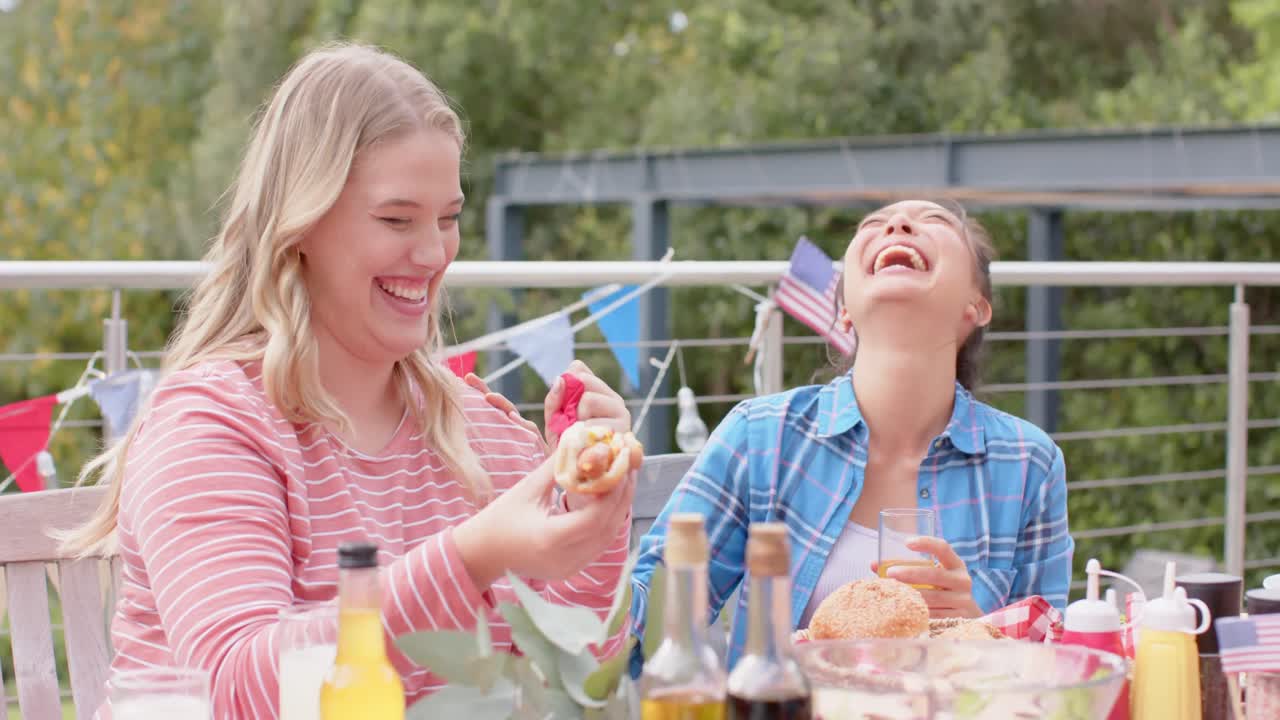 다양한 행복한 여성 친구들이 정원에서 저녁 식사 테이블에서 먹고 이야기하고, 느린 움직임