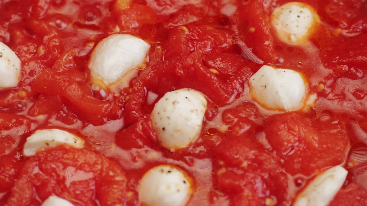 Cooking fresh peeled canned tomato Juice sauce with mozzarella cheese in pan, peeled tomatoes boiling in their own juice, making tomatoes pasta sauce .Top view close up, Italian traditional cuisine food.