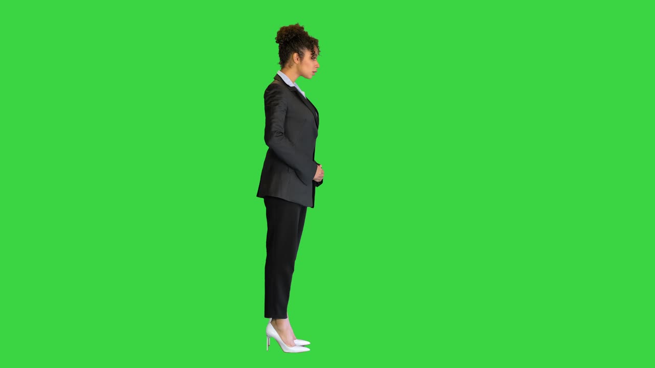 젊은 아프리카계 미국인 여성이 녹색 스크린, 크로마 키에서 카메라를 위해 포즈를 취하고 있습니다.