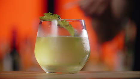 preparing a cocktail with basil garnish