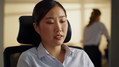 a woman sits at her office desk in the afternoon, concentrating on her tasks with papers and a laptop. the atmosphere is calm and professional, showcasing a productive work environment.