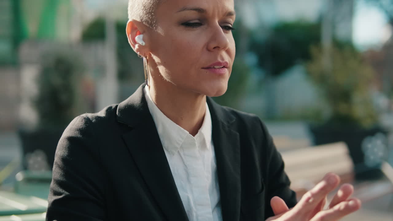 Affarista concentrata parla con auricolari wireless all'aperto.