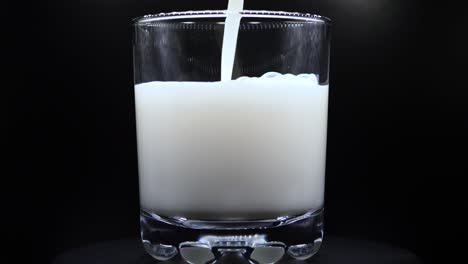 Verter-Leche-Fresca-En-Un-Vaso-Transparente-De-Fondo-Negro