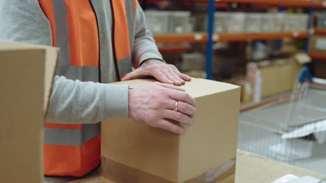 trabajador del almacén empacando y sellando una caja para el envío, destacando el embalaje eficiente