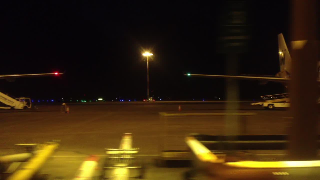 An airport at night. Planes and service personnel on the runway at an airport terminal