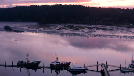 Drone-ascending-sideways-over-commercial-fishing-vessels,-revealing-the-waters-of-the-slough