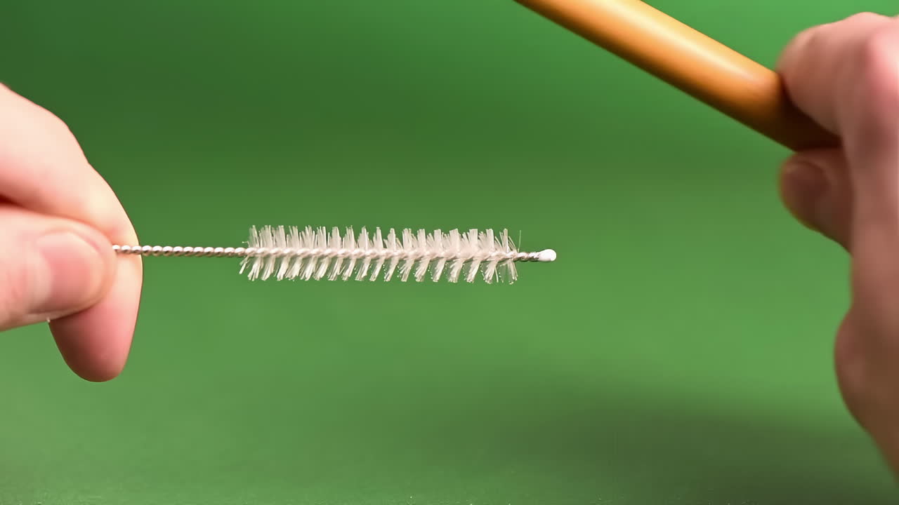 Bamboo straw cleaning with a brush with a green background