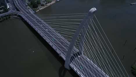 Top-down-aerial-orbit-of-suspension-bridge-over-river-with-road-traffic-in-dramatic-light