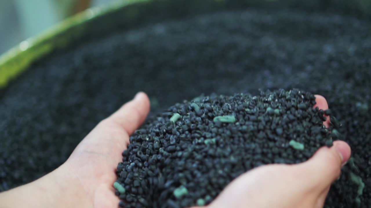 재활용을 위해 녹이는 작은 플라스틱 조각을 다루는 손