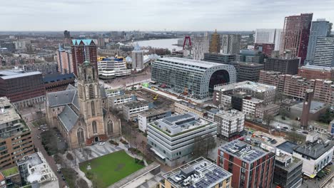 el dron está volando sobre el centro de la ciudad de rotterdam con el markthal en el centro y el río en el fondo en un día nublado en rotterdam, países bajos.