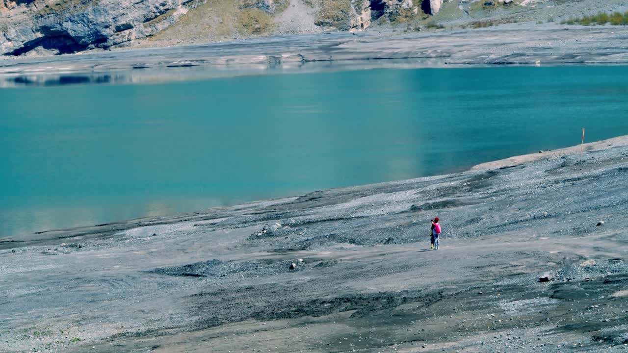 una madre con su hijo caminando hacia este lago azul y frío, tomando fotos y disfrutando de la naturaleza que los rodea