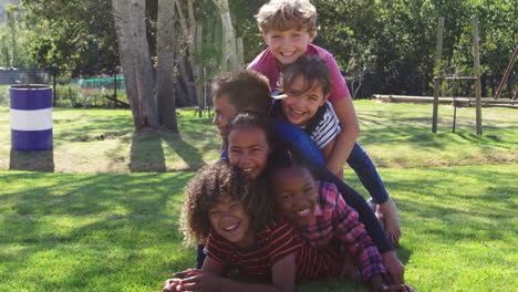 pre-teen school friends lying a pile in a park