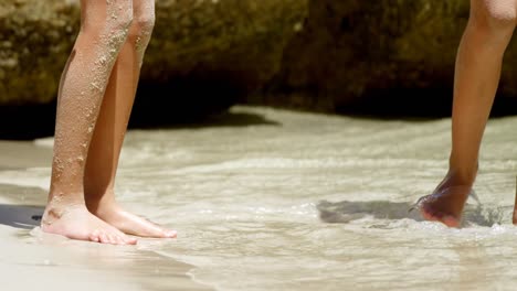 Siblings-standing-in-water-on-the-beach-4k