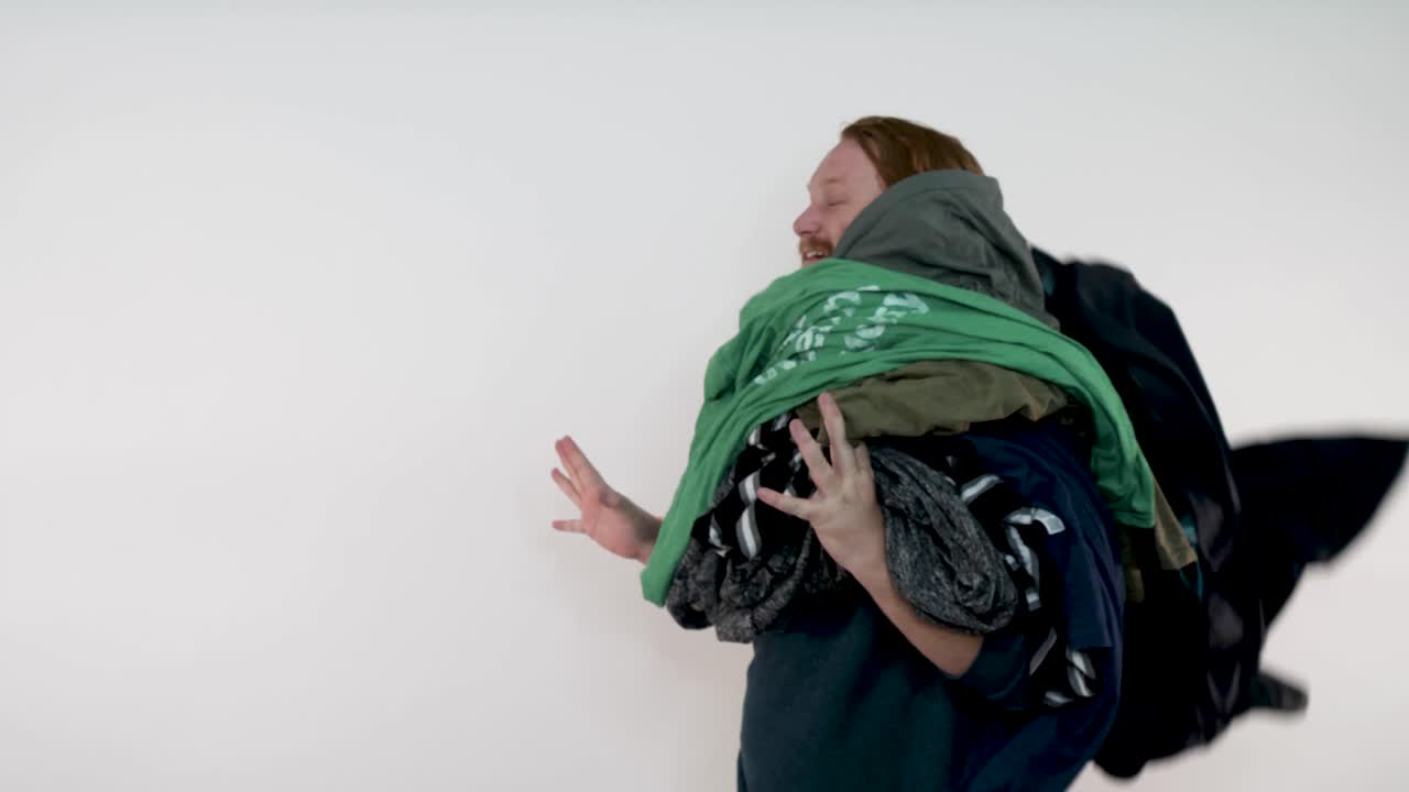 A red-haired man warning as a pile of clothes hits his face