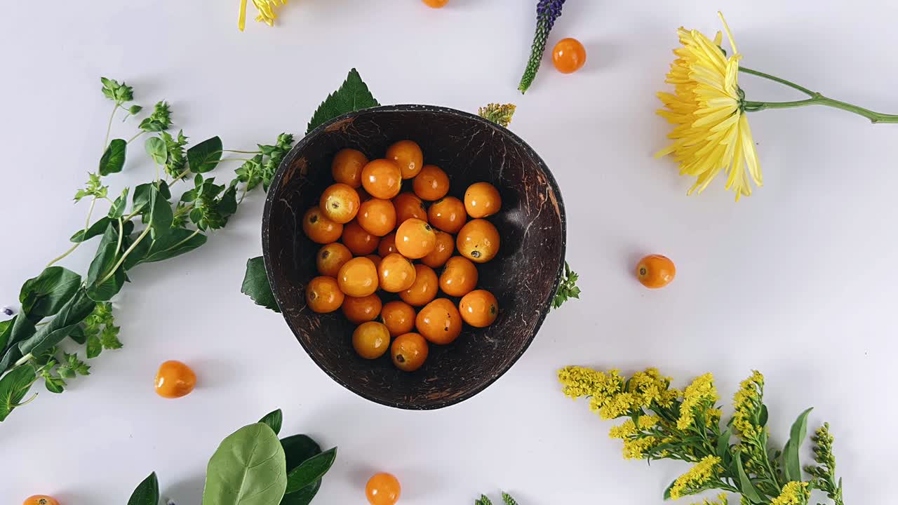 Arrangement of Orange Berries in Coconut Bowl with Flowers and Leaves