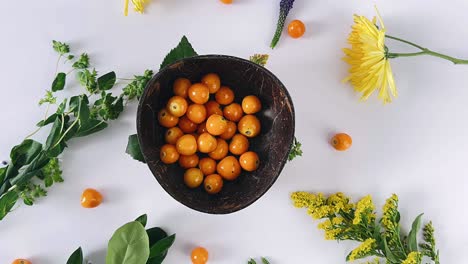 arrangement of orange berries in coconut bowl with flowers and leaves