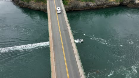 aerial shot of a boat passing underneath the bridge at deception pass