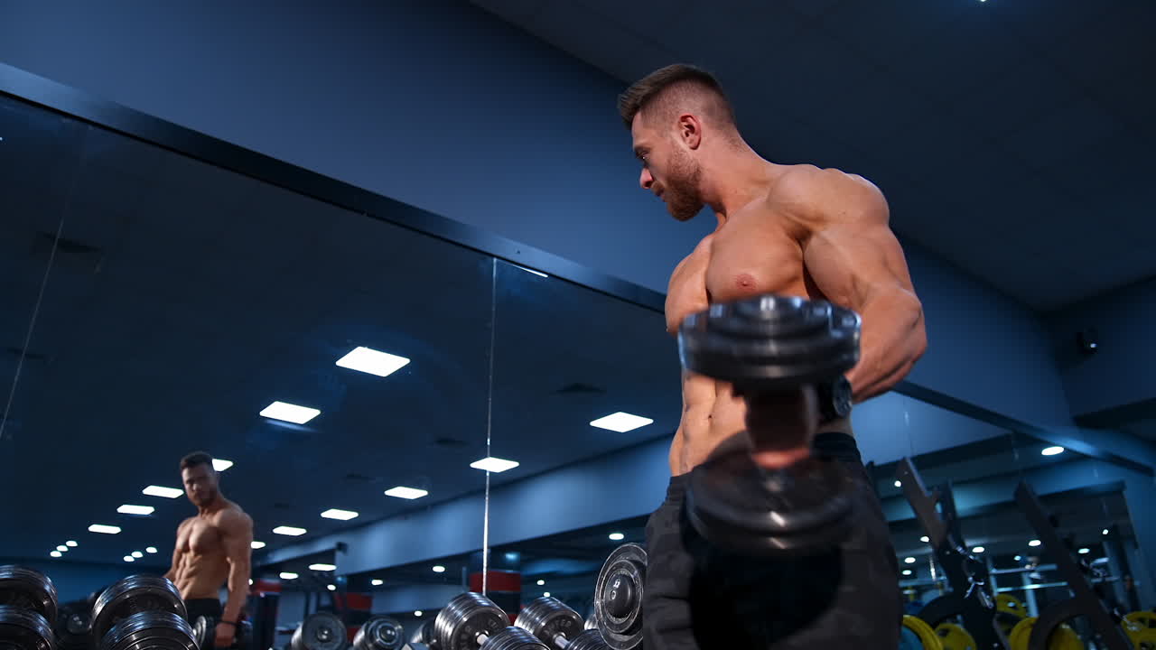 Modello fitness con manubrio. Uomo atletico che si allena con i manubri in palestra.