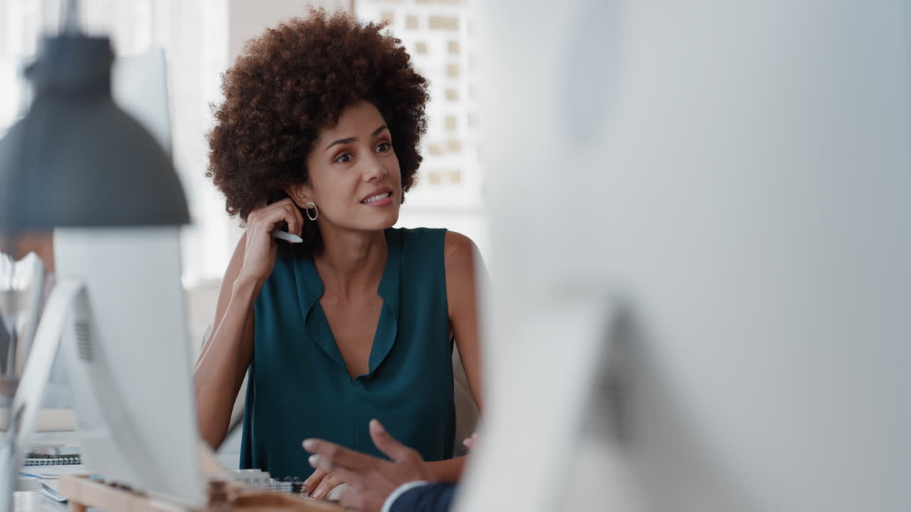 young mixed race business woman with afro chatting to intern discussing job interview colleagues having conversation in office enjoying teamwork