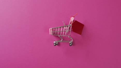 video of shopping trolley with red price tag and copy space on pink background