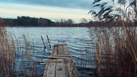 old, wooden catwalk in the lake, against the background of the blue sky and magnificent greens around