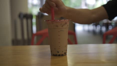 poking through plastic cup of bubble tea cup with a plastic straw