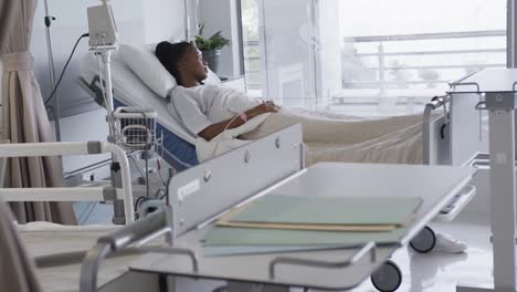 african american female patient lying in bed in hospital room, slow motion