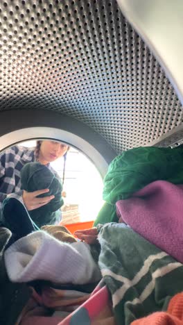 person loading clothes into washing machine