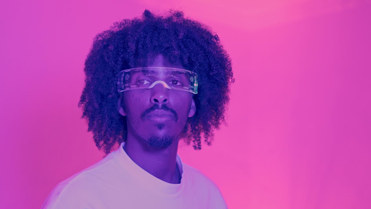 Man with Afro Hair Wearing Futuristic Glasses Against a Pink Neon Background