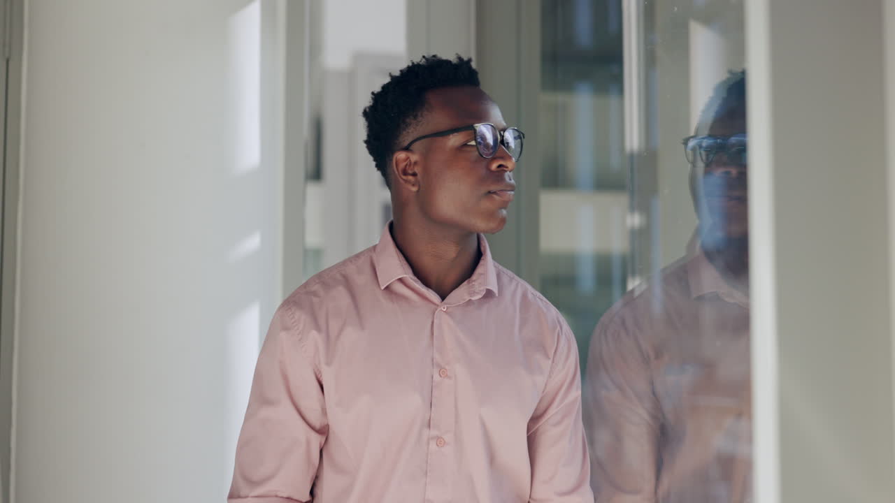 Businessman in office hallway looking out window