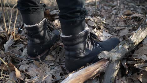 man with boots stepping on leaves on the ground