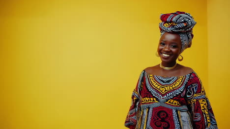 african woman in traditional attire posing for camera on yellow background