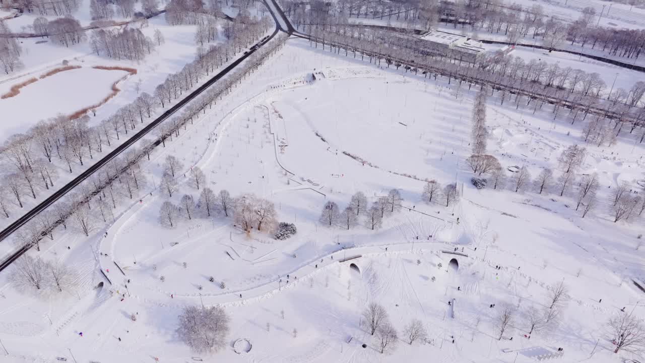 Beautiful winter sunlight and falling snow over ice tracks in Riga Victory Park