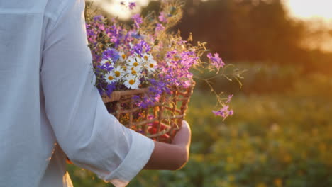 una mujer lleva una canasta con flores silvestres