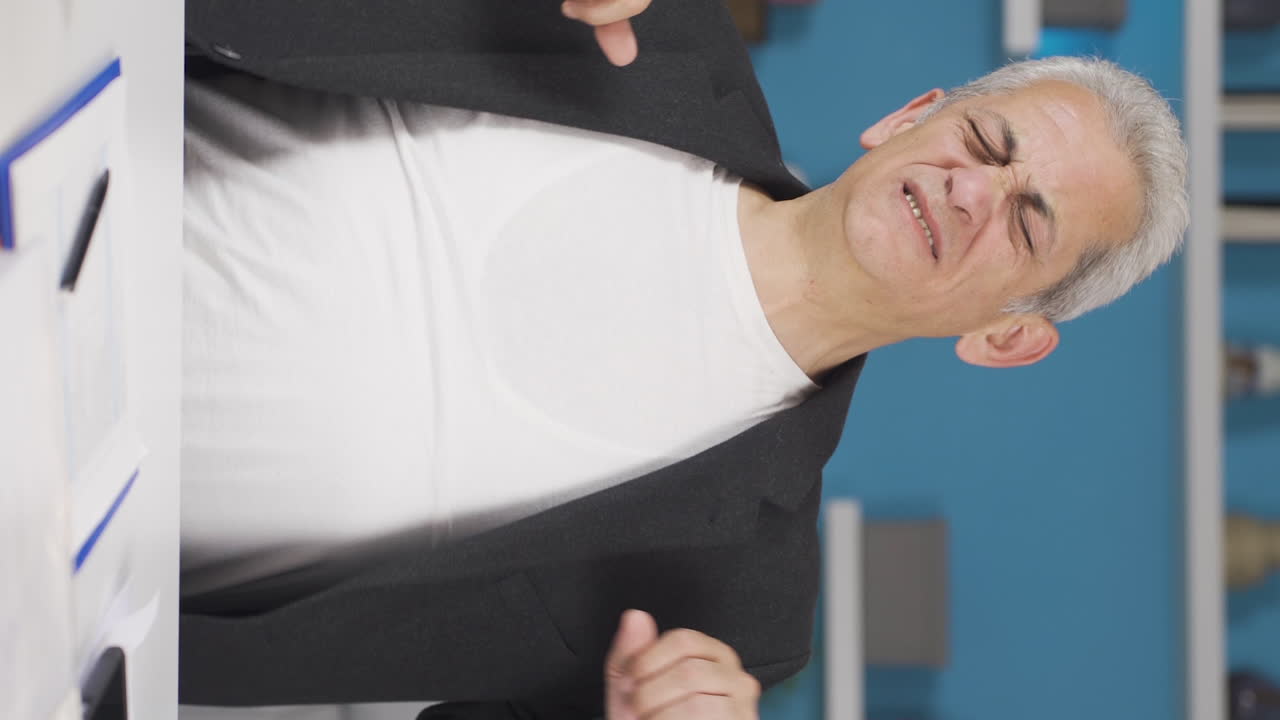 Vertical video of Home office worker man yawns and relaxes at the camera.