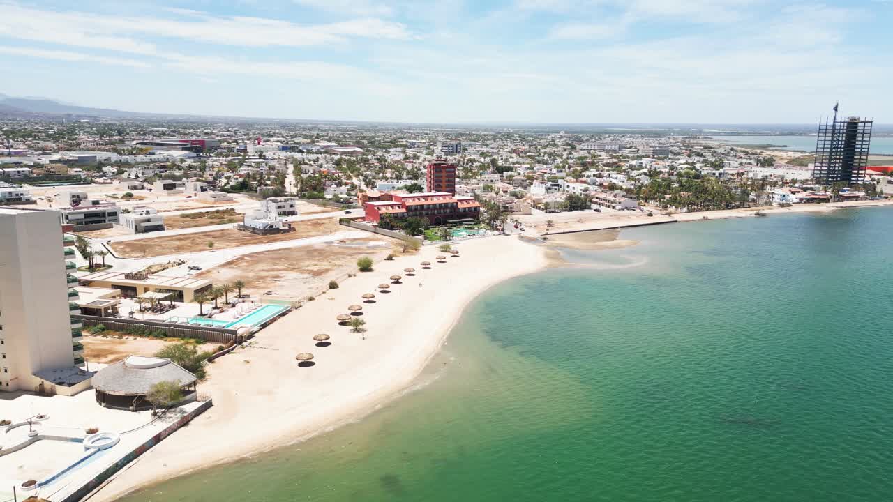 Beachfront hotels and umbrellas along calm Playa Posada in La Paz, Mexico