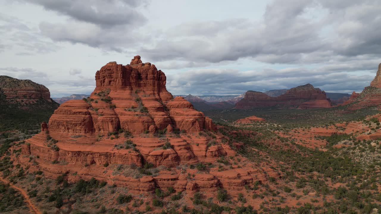 Aerial drone footage of Bell Rock in Sedona, Arizona, featuring iconic red sandstone formation surrounded by desert landscape, rugged cliffs, and stunning views beneath clear blue southwestern skies