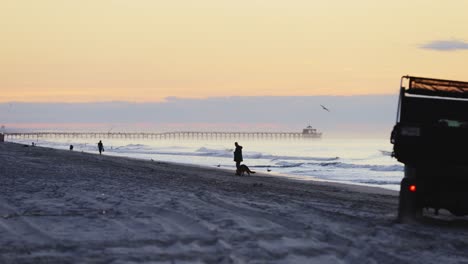 silhouette of beach truck driving on sandy beach during sunrise