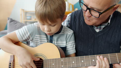 grandfather teaching grandson to play guitar