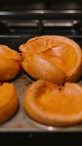 vertical video close up of freshly cooked british yorkshire puddings in rustic tray with texture details visible as camera moves along. traditional english cuisine.