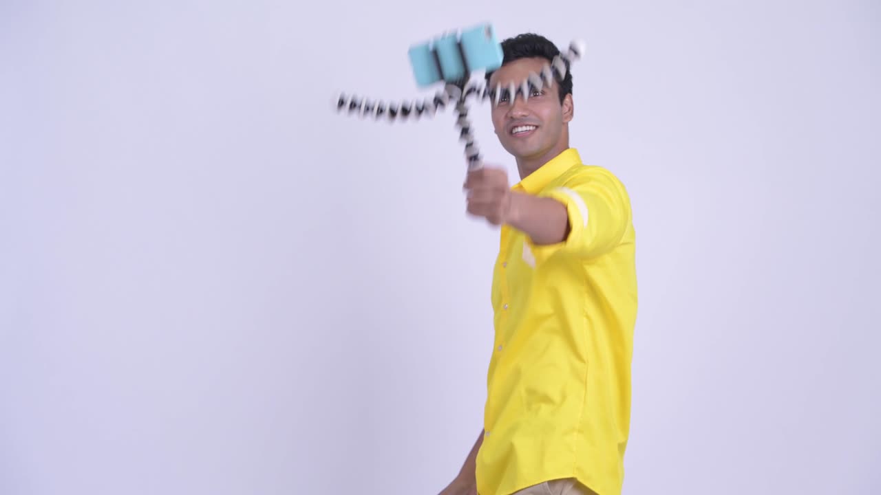 Happy young handsome Indian businessman with phone