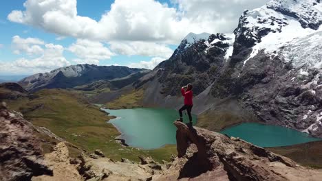 Aerial,-drone-shot-passing-a-woman-drinking-water,-revealing-emerald-lagoons-and-the-Ausangate-glacier-mountain,-on-a-sunny-day,-in-the-Andes,-Peru,-South-America