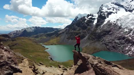 aéreo, disparo de un dron pasando a una mujer bebiendo agua, revelando lagunas esmeralda y la montaña glaciar ausangate, en un día soleado, en los andes, perú, sudamérica