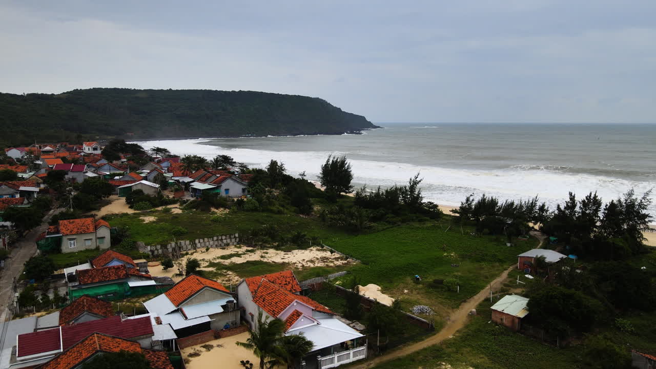 Explore the beautiful coastal village with colorful rooftops and stunning beach views. Lush greenery and peaceful waves create a serene atmosphere in this Vietnamese location