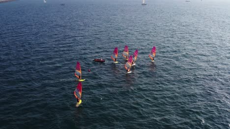 multiple windsurfers standing on a surfboard on the mediterranean sea with colored sails on a sunny day in herzeliya israel on a sunny day